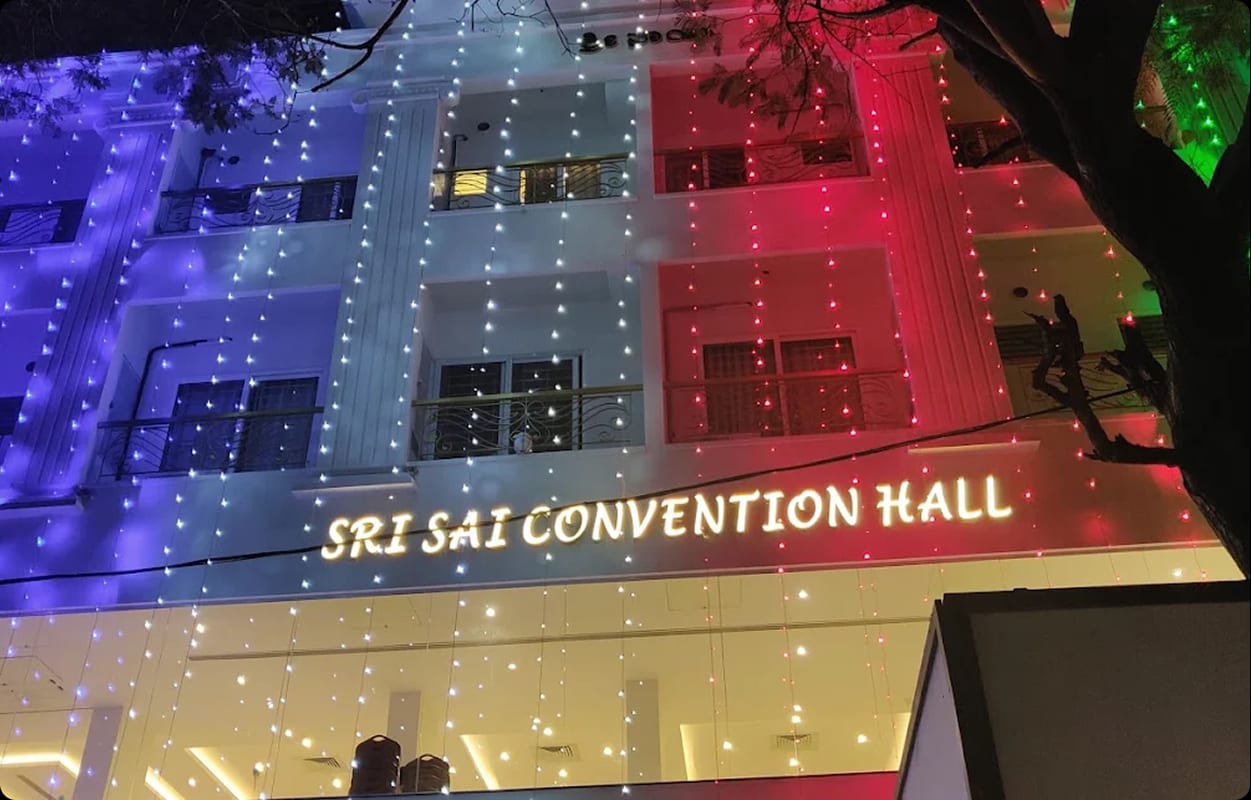 The Sri Sai Convention Hall facade in red and blue celebration lighting with the hall signage above the entrance, Jayanagar, Bengaluru