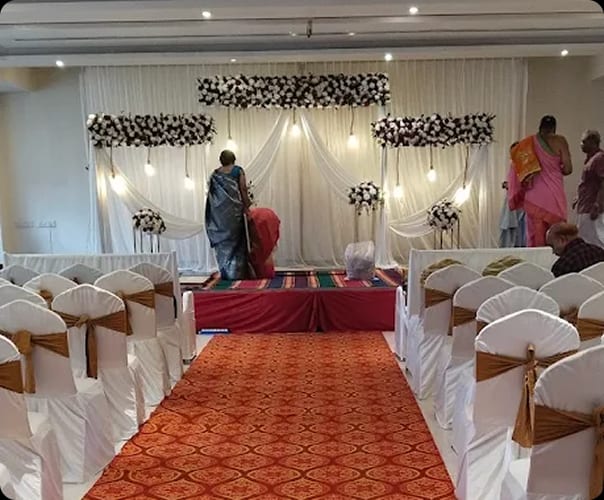Guest seating either side of the red aisle with a floral stage backdrop, Sri Sai Convention Hall, Jayanagar