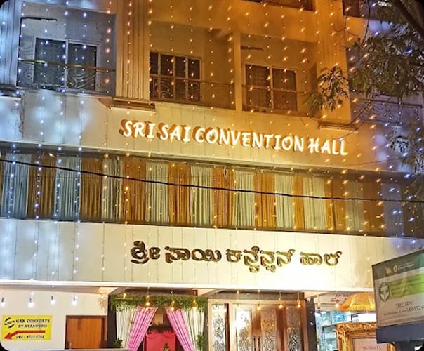 Sri Sai Convention Hall signage in English and Kannada lit at night, opposite Jayanagar 9th Block bus stop, Bengaluru